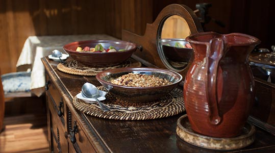 Breakfast of fruit and granola in Calistoga Pottery dishware on wooden dresser in the dining room of the Calistoga Wine Way Inn in the Napa Valley Wine Country