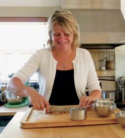 Owner of the Calistoga Wine Way Inn and the Craftsman Inn in Calistoga, CA, in the Napa Valley Wine Country, Gillian Kite, chopping nuts on wooden chopping board for granola for guests of the bed and breakfast in the Craftsman Inn kitchen