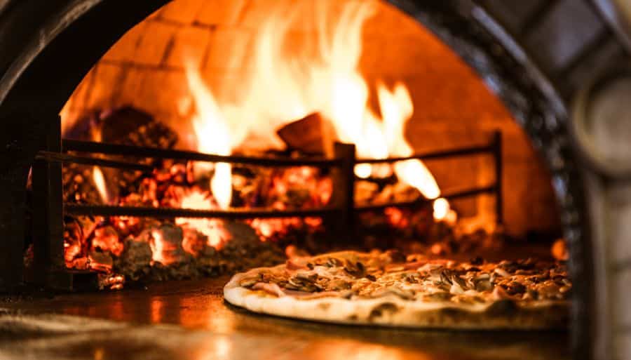 Wood-fired pizza oven with a round meat pizza baking
