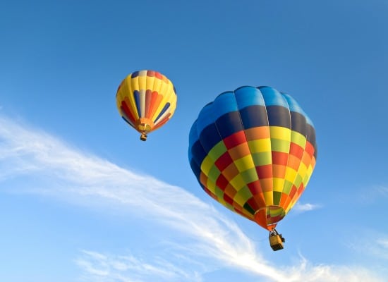 Two hot air balloons floating in a cloudless sky.