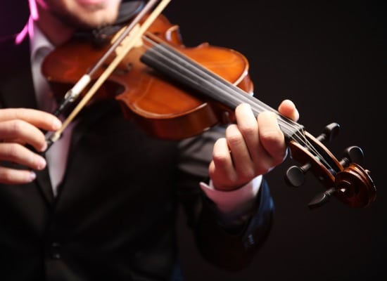 Violinist's performance on black background, close up