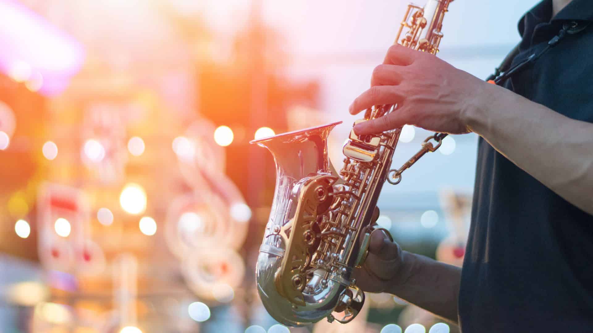 A saxophone player at an outdoor music festival with bright lights