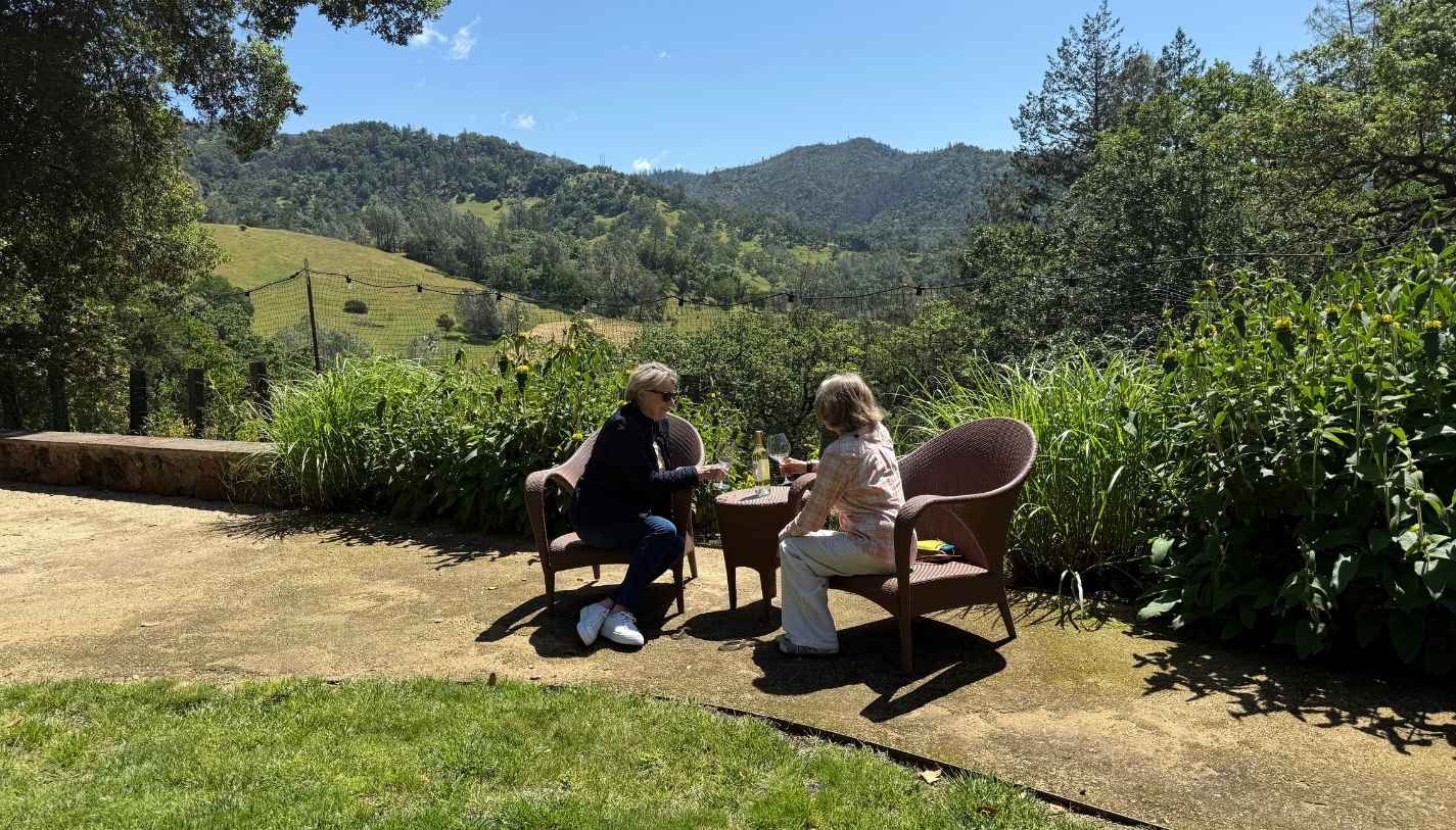 Two women sitting at a table looking over the vineyards at Amici Cellars, a Calistoga winery.