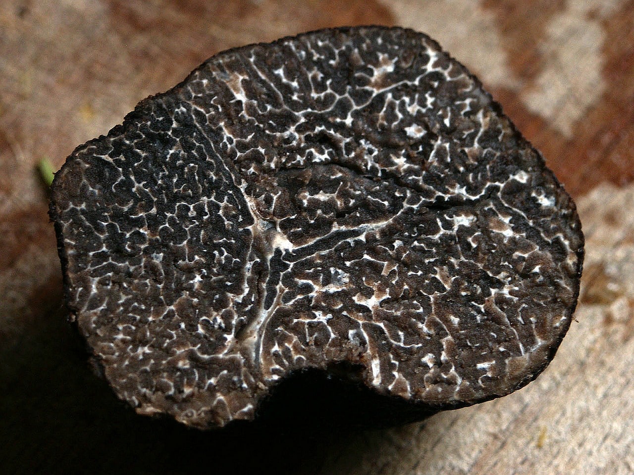 A cross-section of a black truffle on a wooden surface.