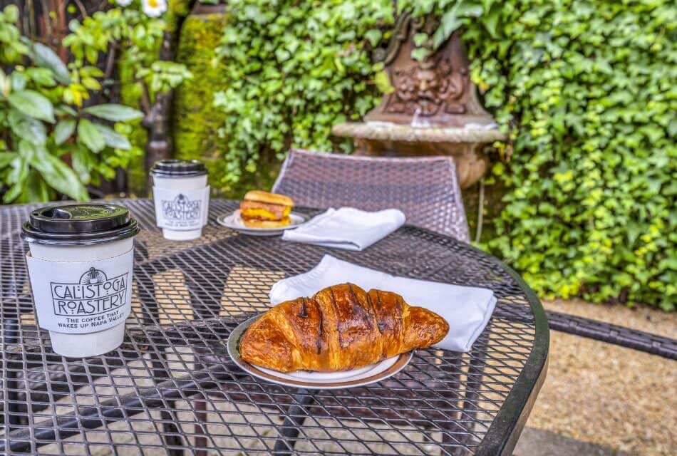 Plate with a chocolate croissant on top of metal patio table