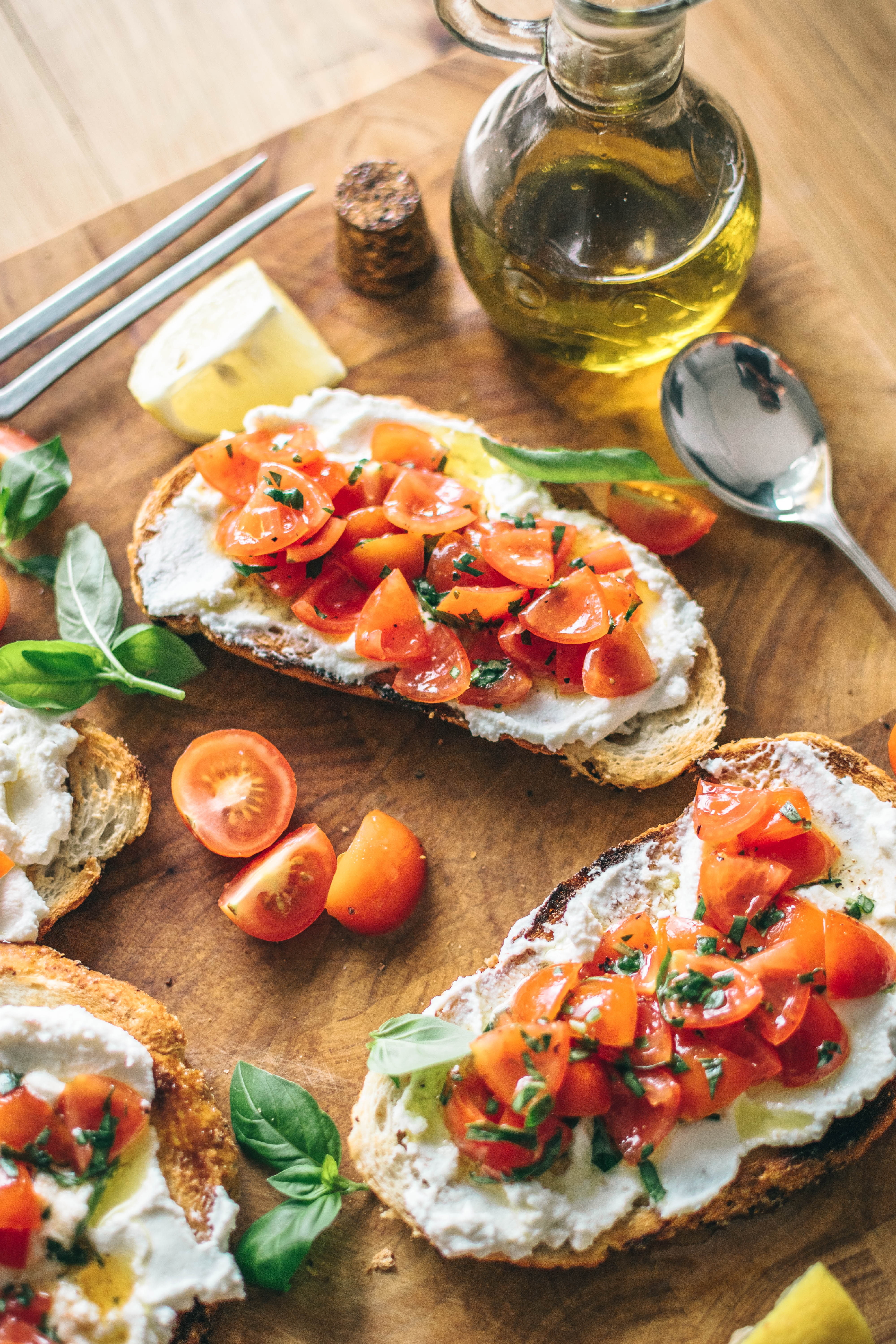 An spread of bruschetta with colorful tomatoes and a small jar of olive oil.