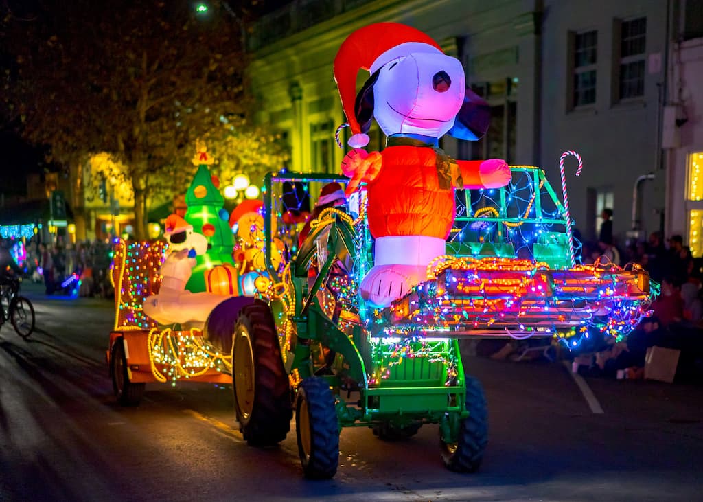 A tractor decorated in Christmas lights, carrying an inflatable Snoopy decoration for the Calistoga Lighted Tractor Parade.