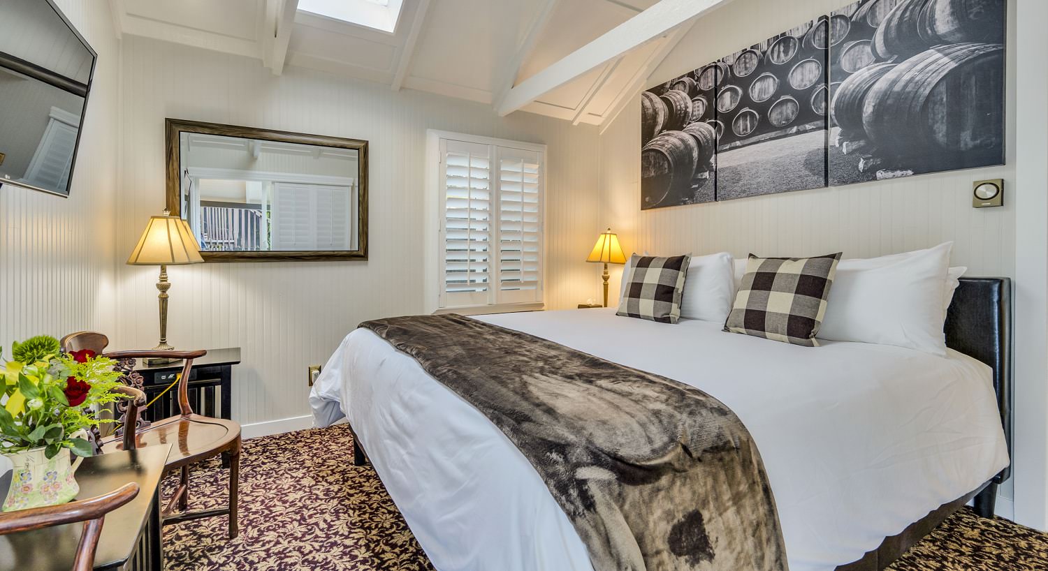 Bedroom with white walls, floral carpeting, white bedding, and sitting area