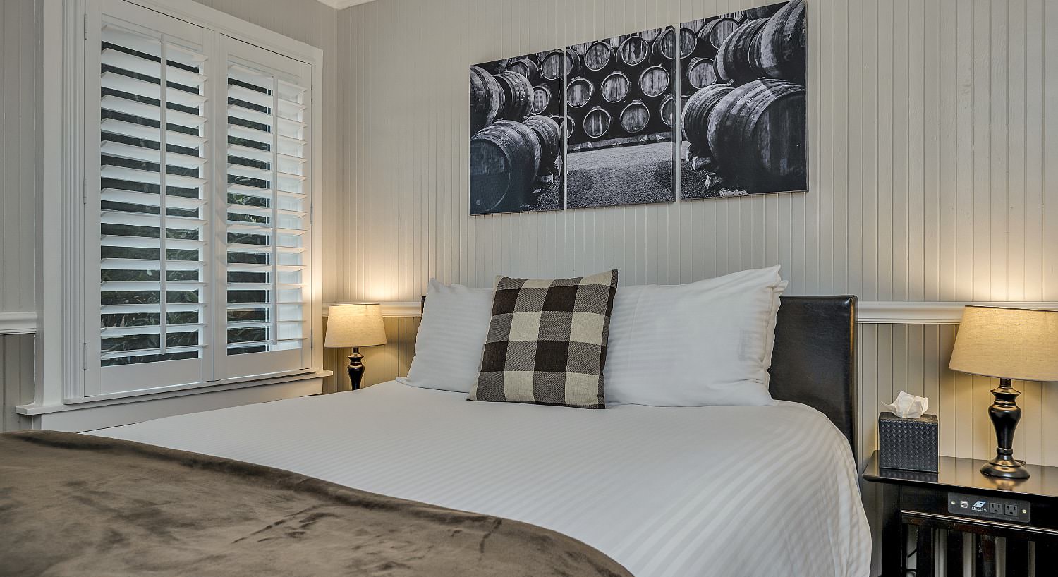 Bedroom with white walls, light gray wainscotting, white bedding, and dark wooden nightstand