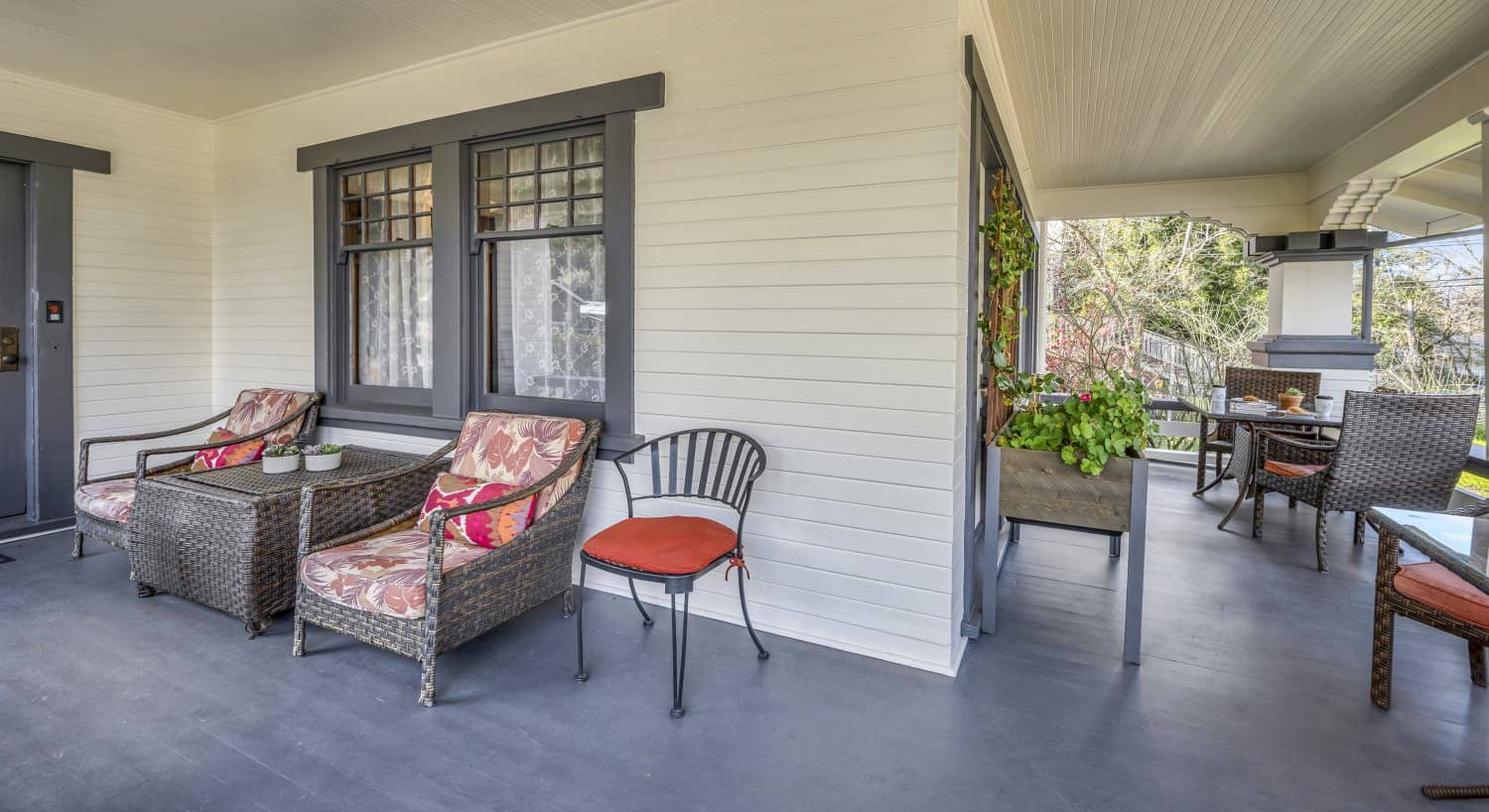 Exterior view of property's front porch with white walls, gray trim, gray flooring, and wicker patio furniture