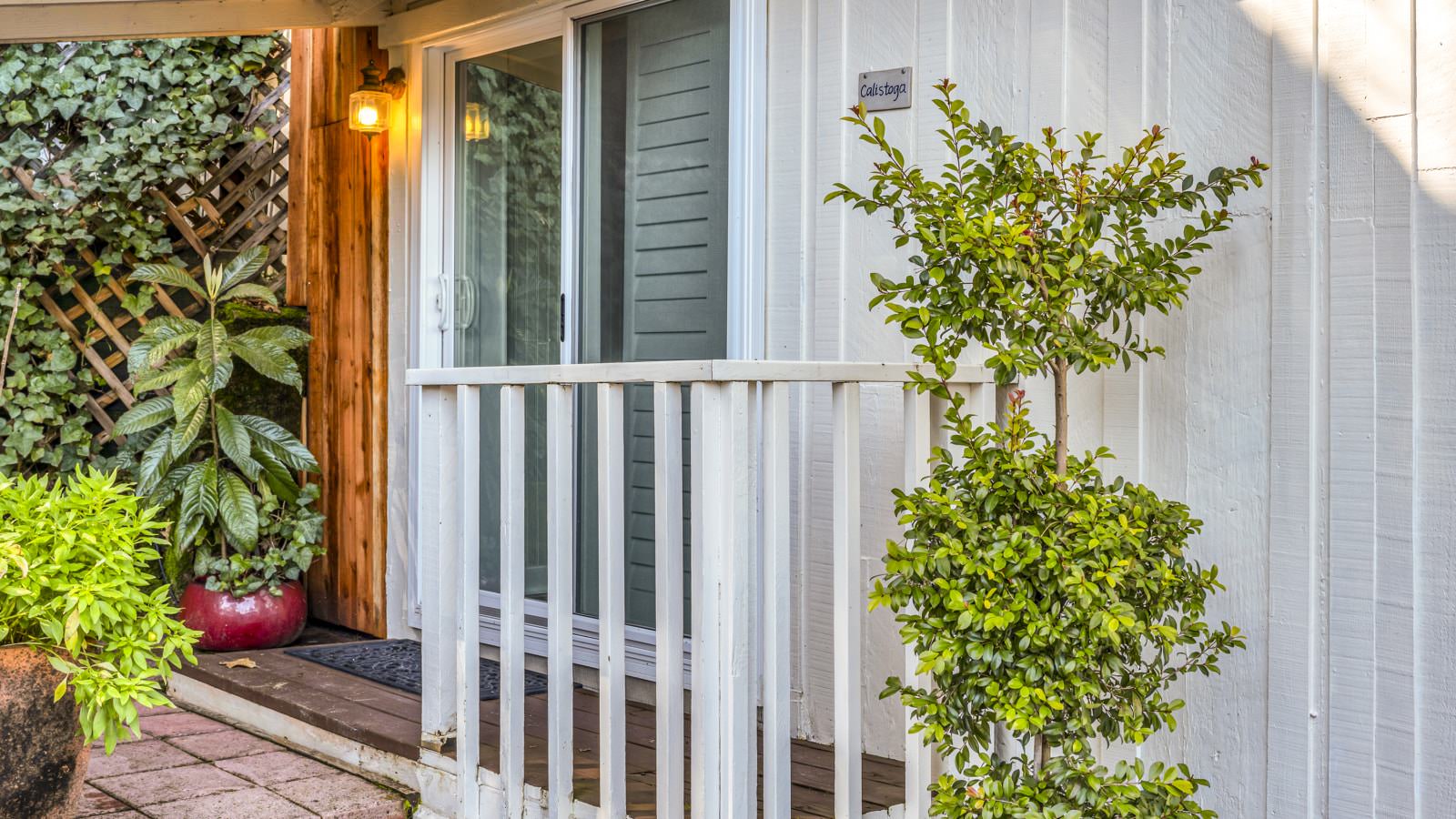 Back patio entrance to Calistoga bedroom surrounded by green potted trees and bushes