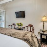 Bedroom with white walls, floral carpeting, white bedding, and dark wooden nightstands