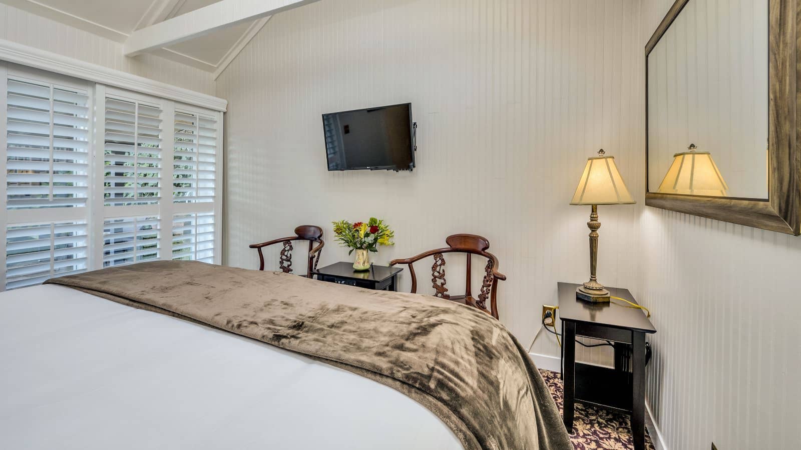 Bedroom with white walls, floral carpeting, white bedding, and dark wooden nightstands