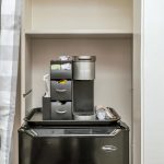 Keurig coffee maker and bag of Keurig pods on top of black mini fridge