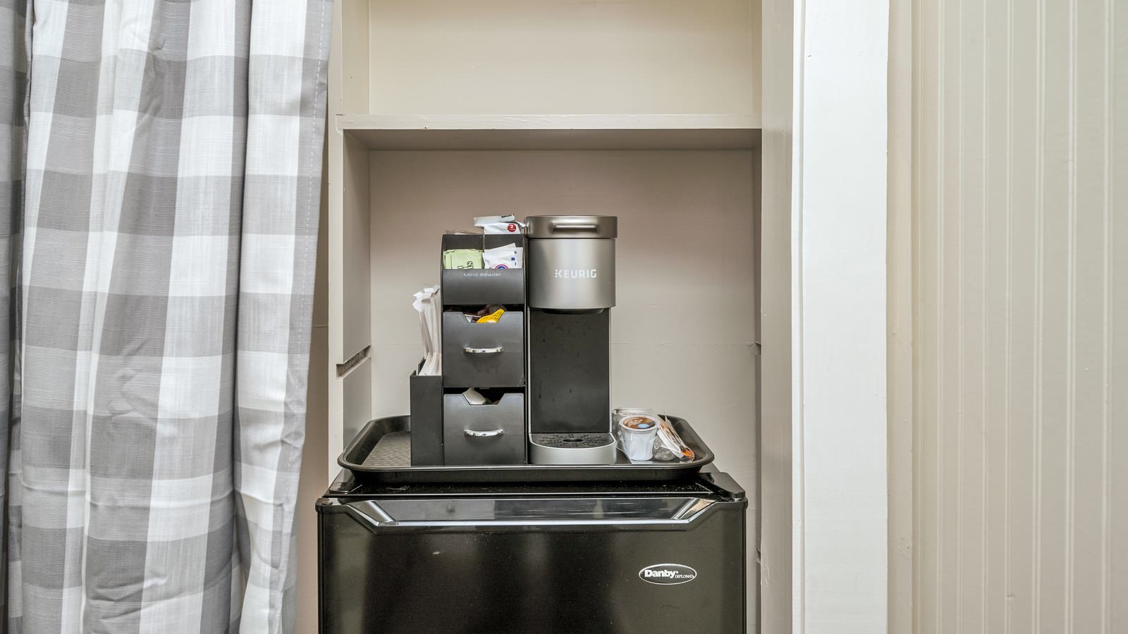 Keurig coffee maker and bag of Keurig pods on top of black mini fridge