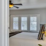 View into bedroom with white walls, light gray wainscotting, and white bedding