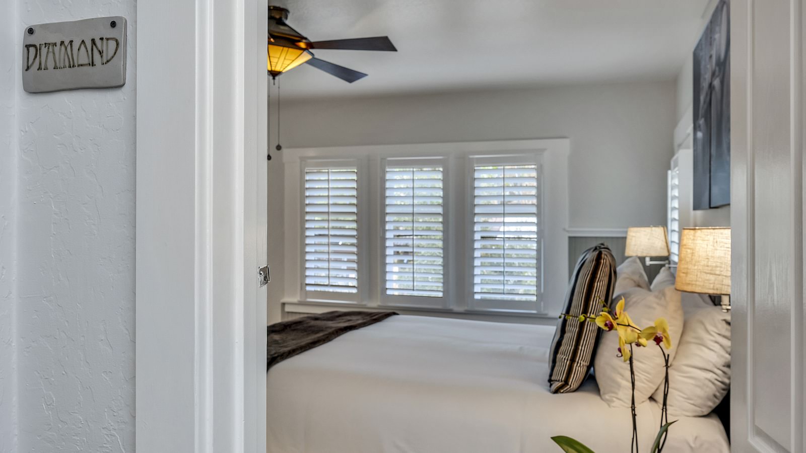 View into bedroom with white walls, light gray wainscotting, and white bedding