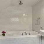 Bathroom with soaker tub surrounded by white tile and white pedestal sink