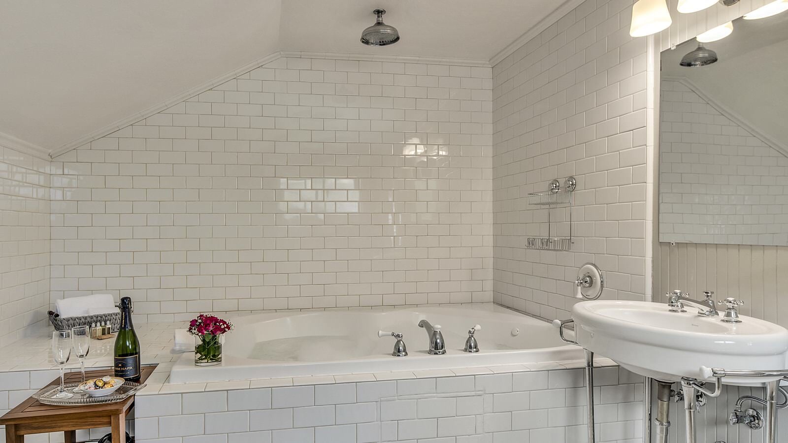 Bathroom with soaker tub surrounded by white tile and white pedestal sink