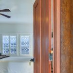 View into bedroom with white walls, white bedding, and dark wooden nightstand