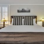 Bedroom with white walls, white bedding, and dark wooden nightstands