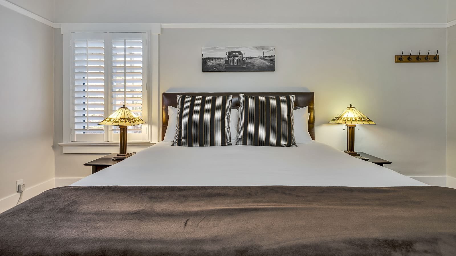 Bedroom with white walls, white bedding, and dark wooden nightstands