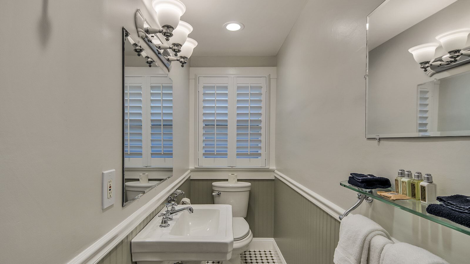 Bathroom with white walls, light gray wainscotting, white sink, and white toilet