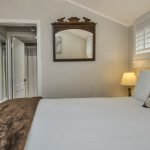 Bedroom with light gray walls, white bedding, and nightstand with lamp