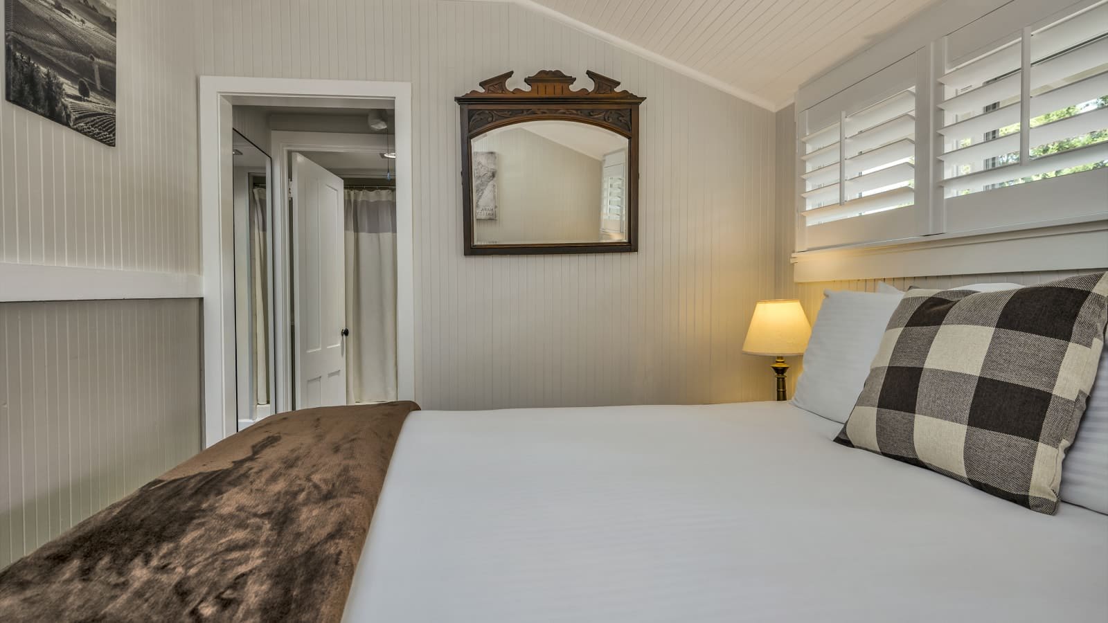 Bedroom with light gray walls, white bedding, and nightstand with lamp