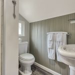 Bathroom with gray and white walls, stand up shower, white toilet, and white sink