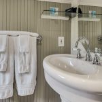 Close up view of white sink and towel bar with white towels