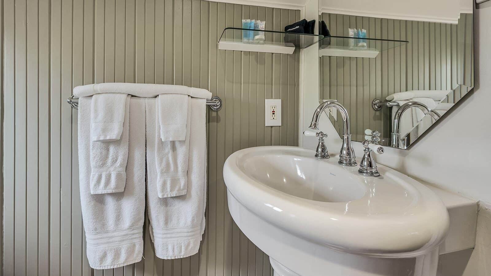 Close up view of white sink and towel bar with white towels