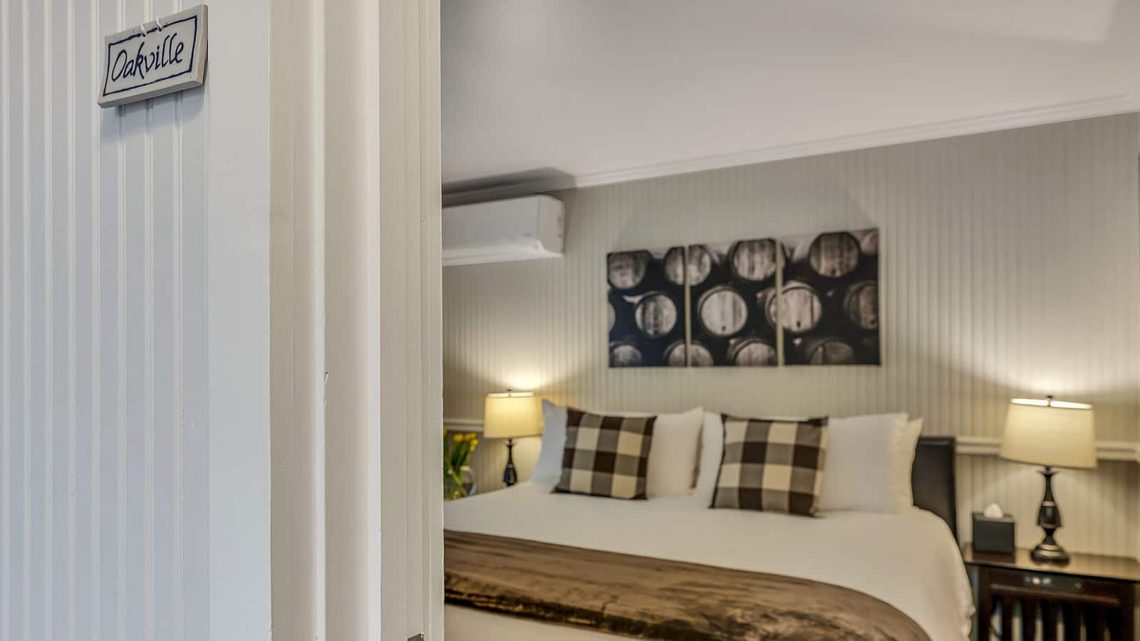 View into bedroom with gray walls, white bedding, and dark wooden nightstands