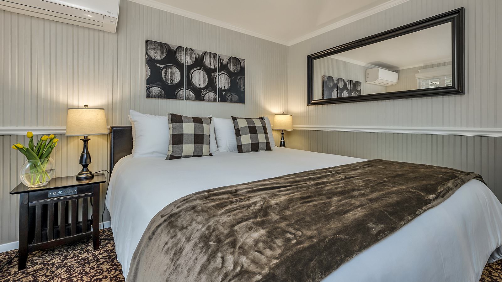 Bedroom with white walls, light gray wainscotting, floral carpeting, white bedding, and dark wooden nightstands