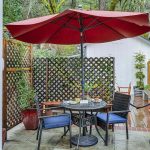 Back patio with metal patio dining table, dark wicker patio dining chairs, and red umbrella