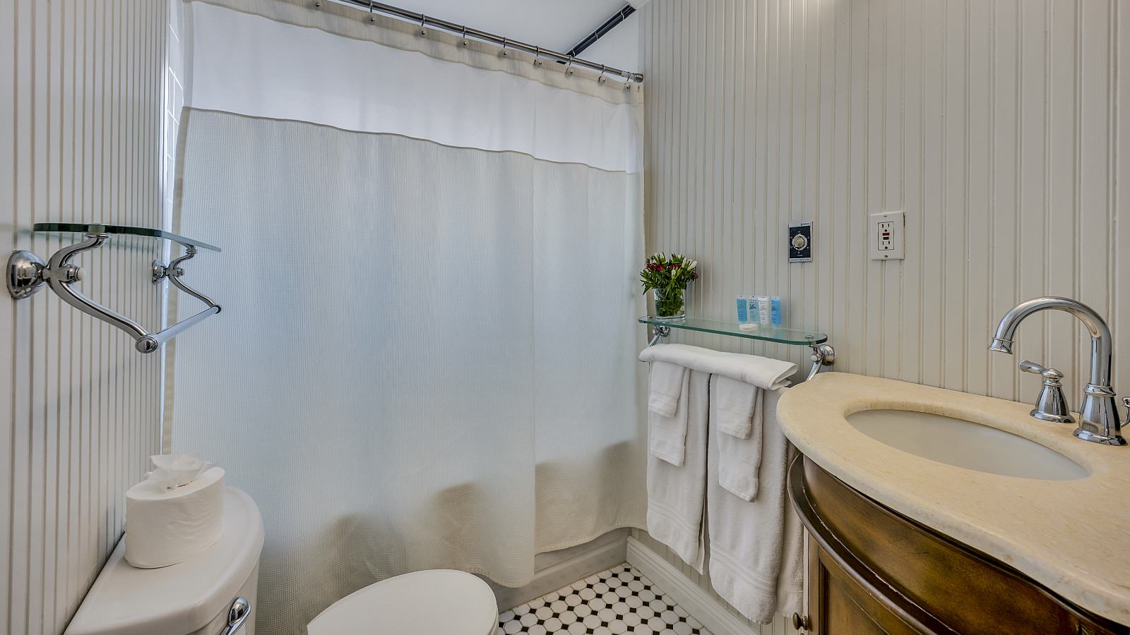 Bathroom with light gray walls, tub and shower combo, white toilet, and wooden vanity with light cream counter