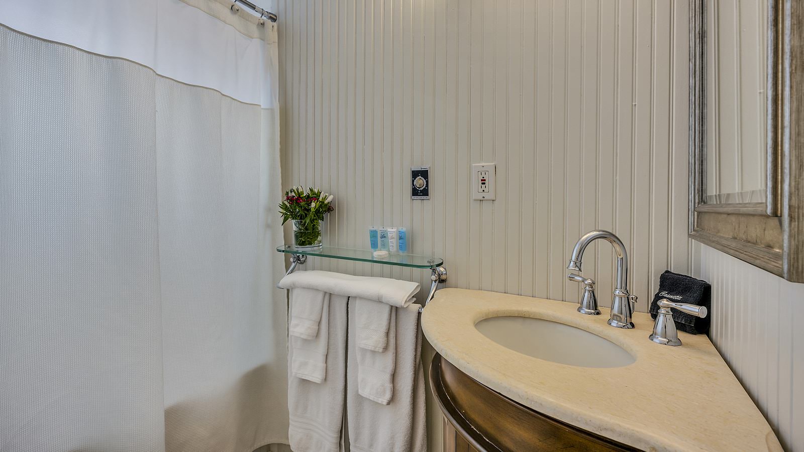Bathroom with light gray walls, tub and shower combo, white toilet, and wooden vanity with light cream counter