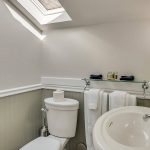 Bathroom with white walls, light gray wainscotting, white toilet and white sink