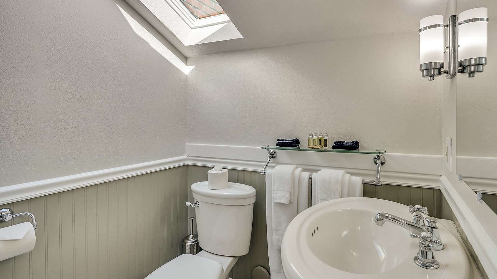 Bathroom with white walls, light gray wainscotting, white toilet and white sink