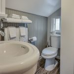 Bathroom with gray and white walls, stand up shower, white toilet, and white sink