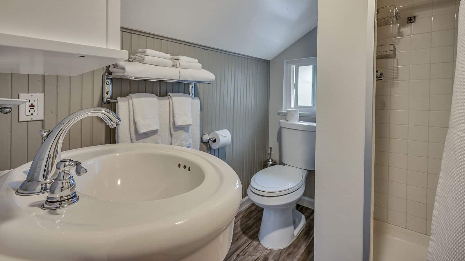 Bathroom with gray and white walls, stand up shower, white toilet, and white sink