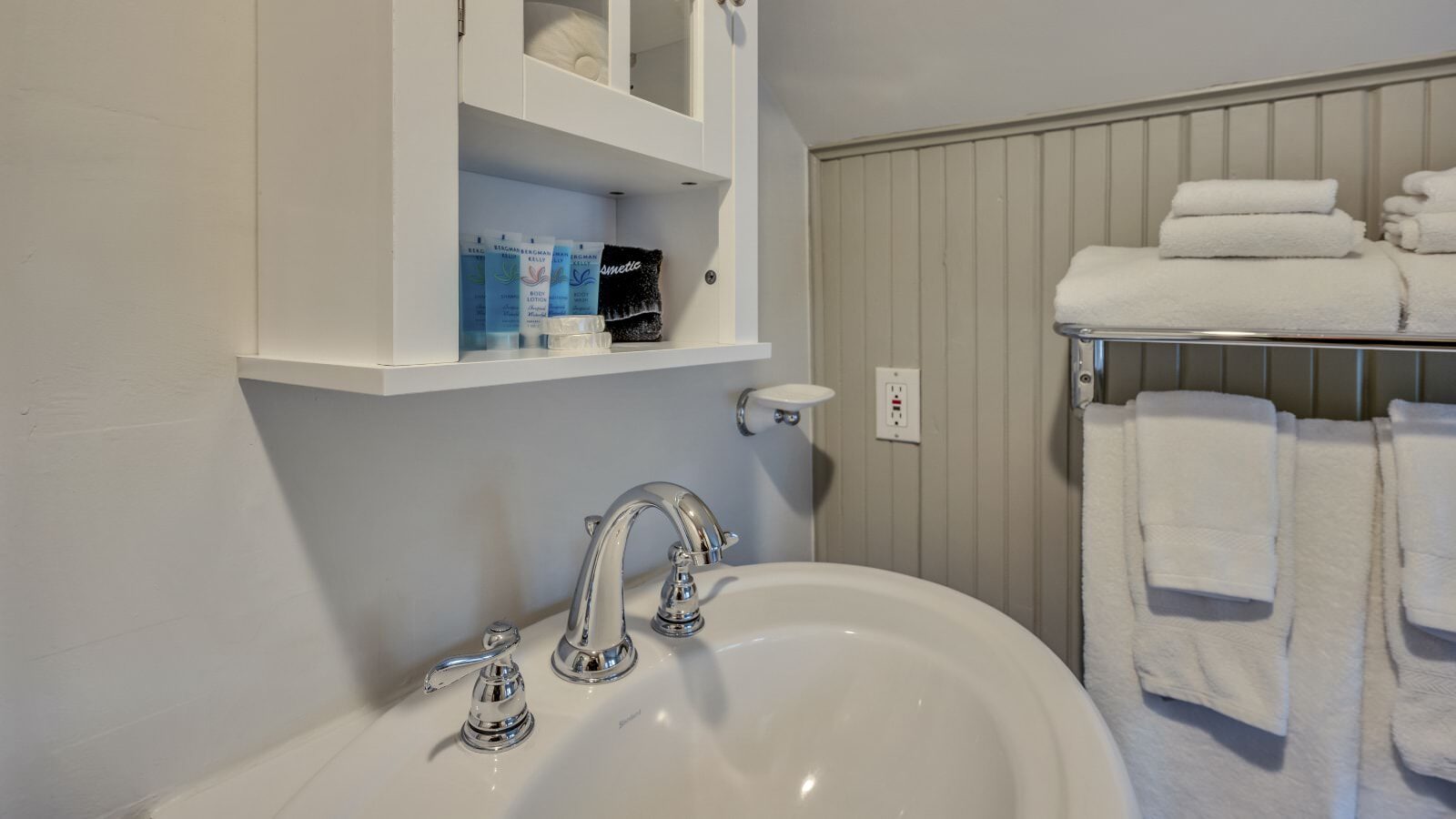 Close up view of white sink, white medicine cabinet, and towel bar with white towels