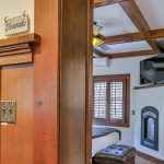 View into bedroom with white walls, light colored carpeting, white bedding, and electric fireplace