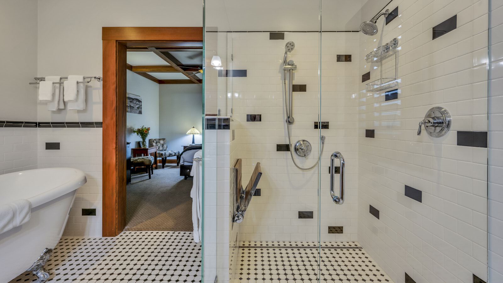 Bathroom with white walls, black and white tiled floor, black and white tiled shower, and white clawfoot tub