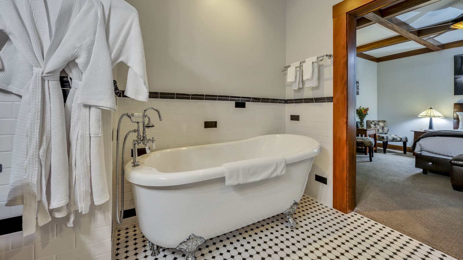 Bathroom with white walls, black and white tiled floor, and white clawfoot tub