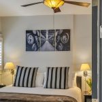 View into bedroom with white walls, white bedding, and dark wooden nightstands