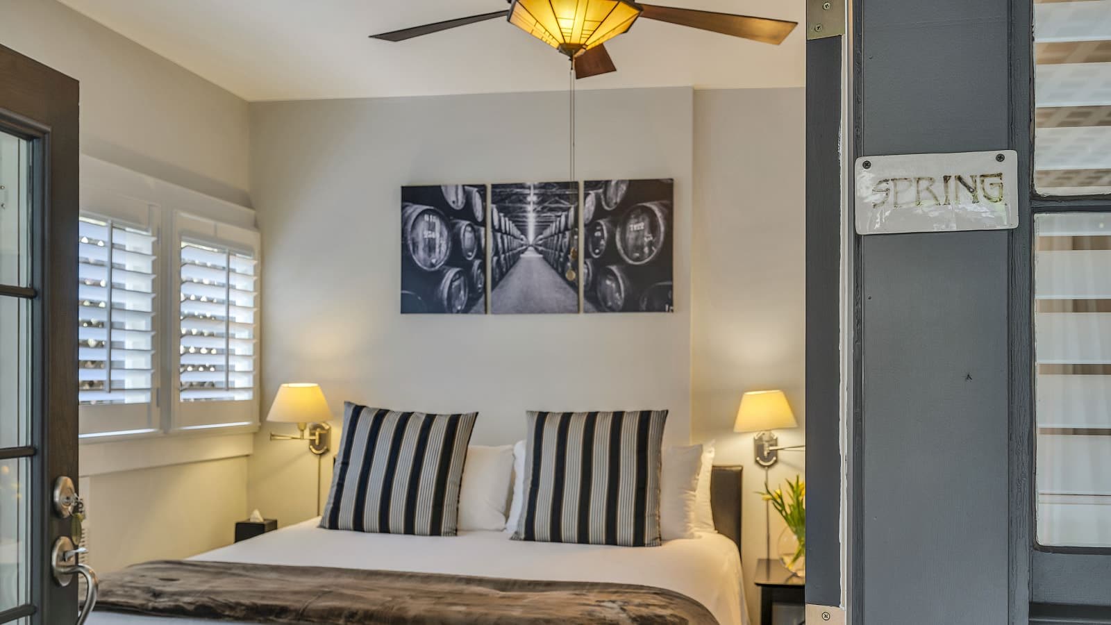 View into bedroom with white walls, white bedding, and dark wooden nightstands