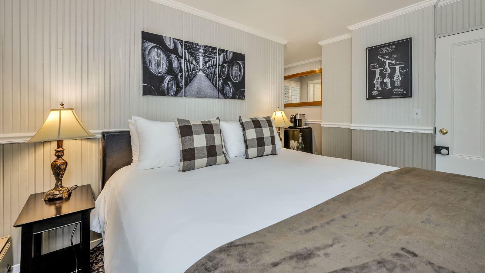 Bedroom with white walls, light gray wainscotting, floral carpeting, white bedding, and dark wooden nightstands