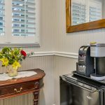 Keurig coffee maker and bag of Keurig pods on top of black mini fridge next to wooden table