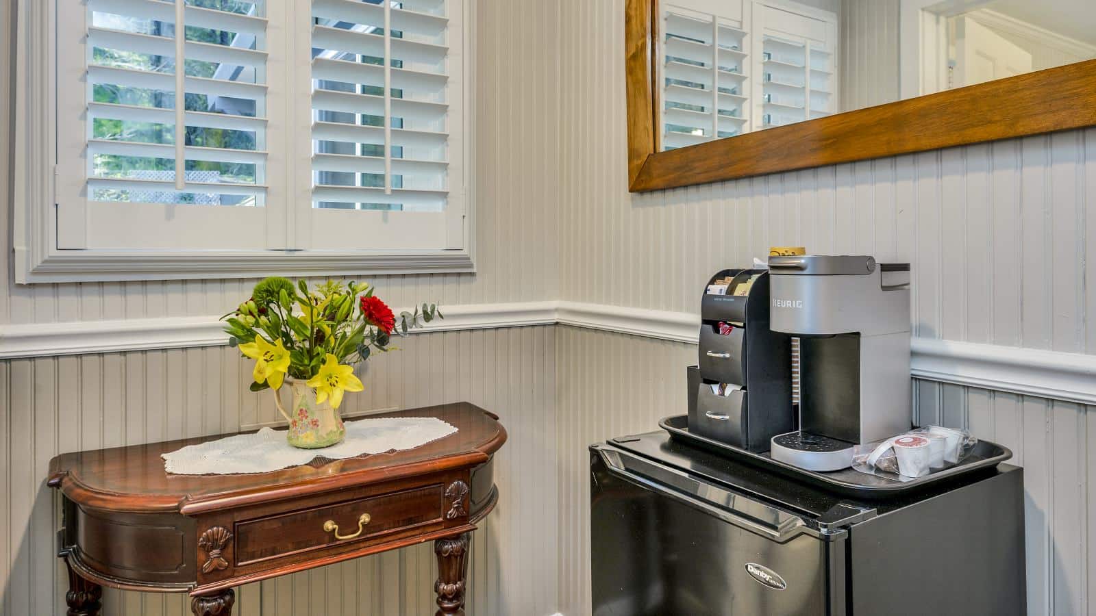 Keurig coffee maker and bag of Keurig pods on top of black mini fridge next to wooden table